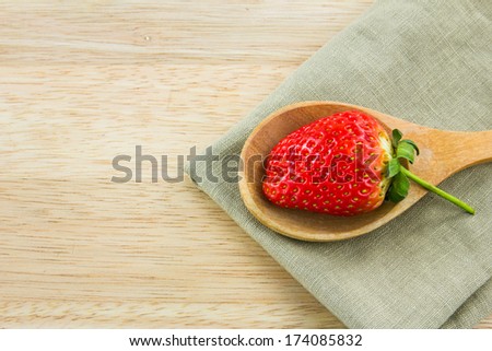 Strawberry on wood spoon with napkin on  wood background.
