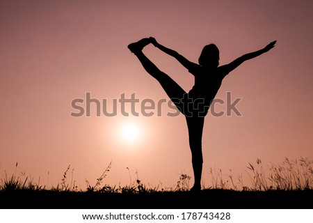 Triangle pose yoga with young woman silhouette on sunset sky.
