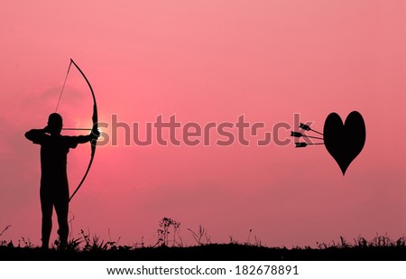 Silhouette archery with a bow shoots the arrows at the heart shape target in the pink sky and cloud.