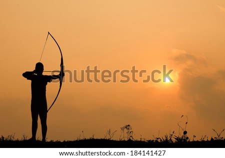 Silhouette archery shoots a bow at a target in sunset sky and cloud.