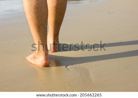 Man leg with footprint on beach background.