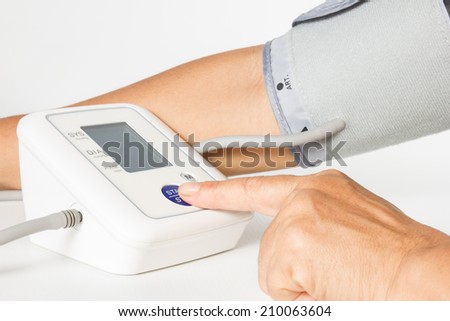 Female hands press start button on blood-pressure meter isolated on white background.