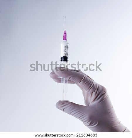 Hand in glove with syringe, health care and medical concept.