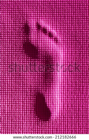 Abstract foot printed on pink yoga mat background.