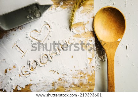 Wooden spoon and starch on board with I love cooking message.