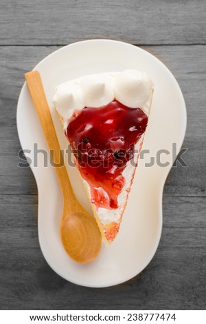 Strawberry cheese cake in white dish with spoon on the wood table.