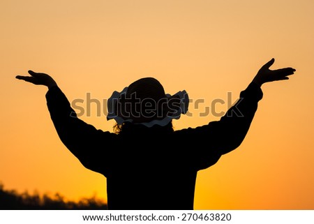 Silhouette woman open hands up to sunset sky background.