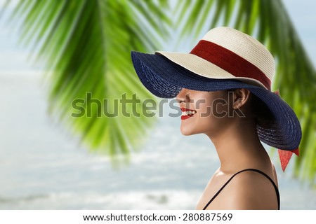 Young Asian woman wearing straw hat with palm leaves and sea background.