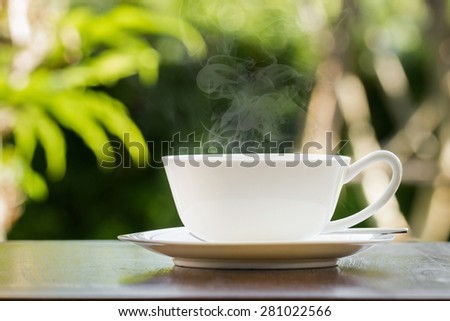 White coffee cup with steam on table in the morning.
