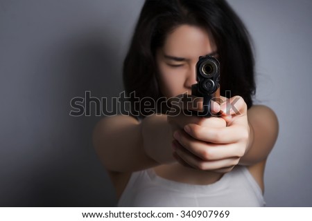 Woman aiming a gun; focus on the gun.