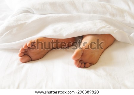 Under the covers with feet showing in a bed