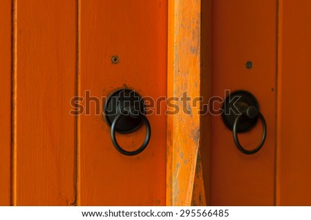 orange painted wooden door with old bronze handles and locks.