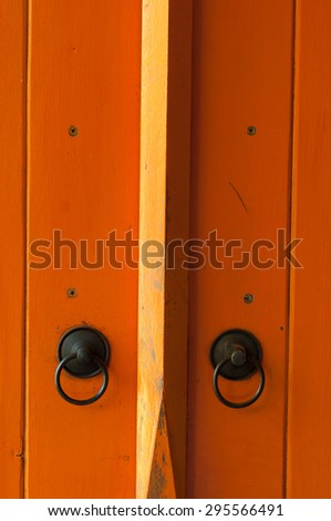 orange painted wooden door with old bronze handles and locks.