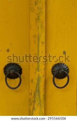 yellow painted wooden door with old bronze handles and locks.