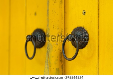 yellow painted wooden door with old bronze handles and locks.