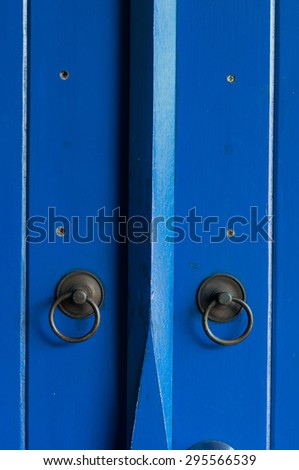 Blue painted wooden door with old bronze handles and locks.