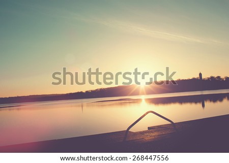 Sunrise on a lake with jetty for excursion boats