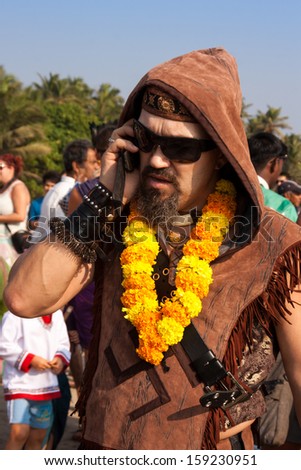 ARAMBOL, GOA, INDIA - FEB. 5: An unidentified man in a necklace of flowers and sun glasses talking on the phone at the annual festival of Freaks on FEB. 5, 2013 in Arambol beach, Goa, India
