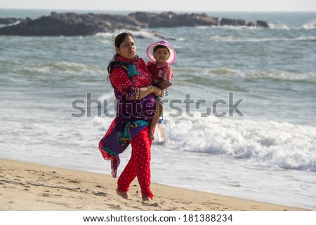 GOA, INDIA - JAN. 10,2014: Unknown  Indian woman is with a baby by the sea shore in Goa, India on JAN. 10, 2014