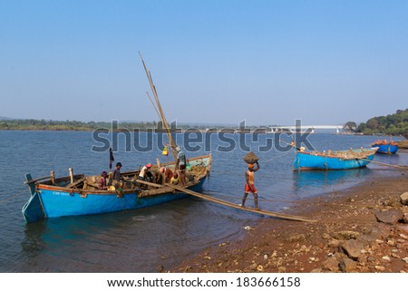 GOA, INDIA - MAR. 15, 2014: Unidentified people carry mined sand on Tirakol River, Goa, India on MAR. 15, 2014 . On boats is mined river sand, which is used in the construction of buildings.