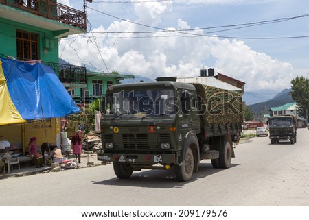 BAHANG, HIMACHAL PRADESH, INDIA, 2 AUG 2014: Military trucks drive on the highway Manali - Leh through the village Bahang. District Manali, Himachal Pradesh, India.