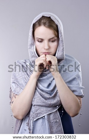 lovely young blonde in a pale blue scarf on her head on gray background