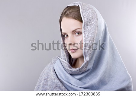 lovely young blonde in a pale blue scarf on her head on gray background
