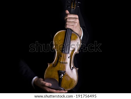 beautiful male hands holding a beautiful polished violin in darkness