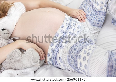 young pregnant woman luxuriates in a white bed.Woman Bed Portrait.Beautiful pregnant curly blonde