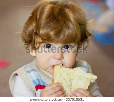 baby with a piece of bread in his hands. Little boy touching the bread. The child smelling a bread