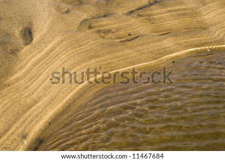 Sand Pattern - Linear pattern in sand with water in foreground