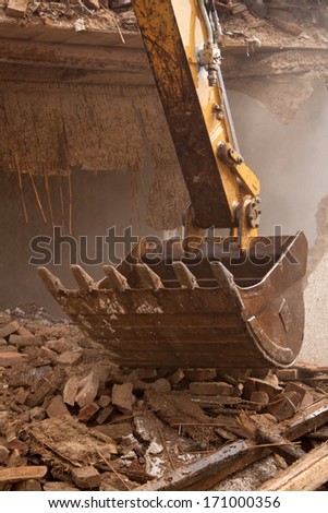 A large track hoe excavator tearing down an old house