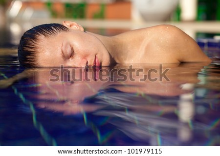 Beautiful young woman in the pool. Left half of her face and shoulder above the water