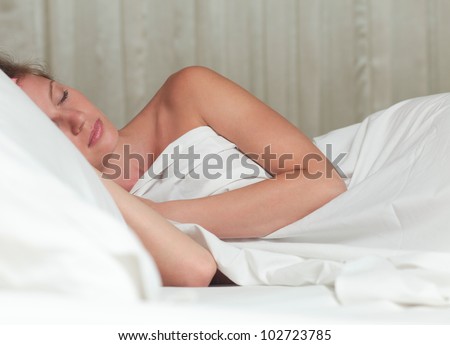 A young attractive woman sleeping on a bed with white sheets