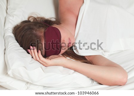 A young attractive woman sleeping on a bed with mask for sleep