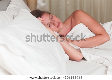 A young attractive woman sleeping on a bed with white sheets
