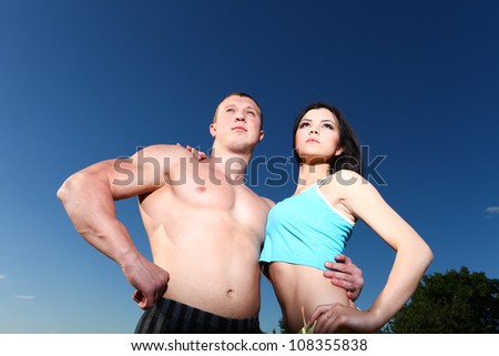 Beautiful athletic man and woman standing next to each other against the blue sky