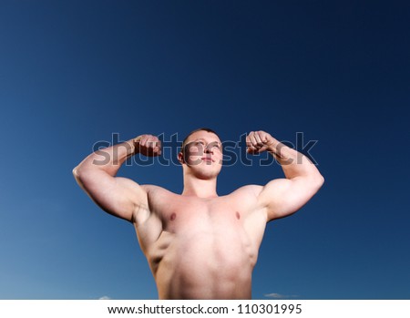 A handsome young and muscular man standing with his hands up