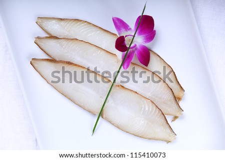 Fresh white fish decorated with spring onion and flower. Close-up