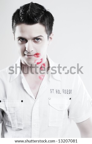 Red kisses on face of young man at white background