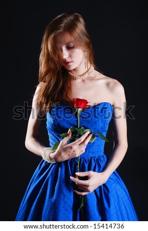 Beauty young woman in blue dress with rose at black background