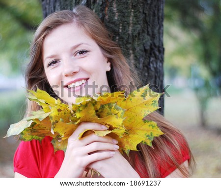 young happy beautiful woman in red with yellow maple leaves
