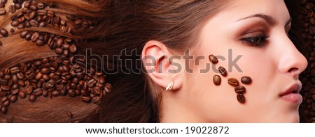 coffee beans on the hair and face of beautiful young woman