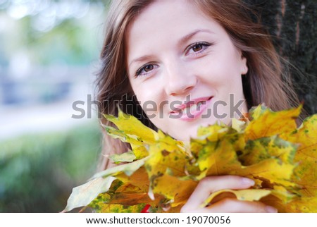 young happy beautiful woman with yellow maple leaves