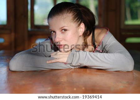 beautiful woman leans on elbows on a table near the window