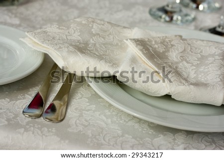 white plate with elegant napkins and silver flatware