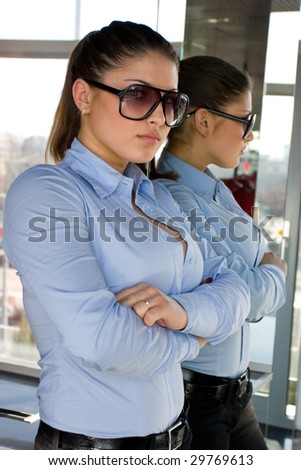 beautiful woman in sunglasses standing near the mirror