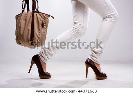 Legs of woman and bag at white background