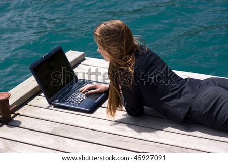 woman in black business suit lying with laptop near the sea