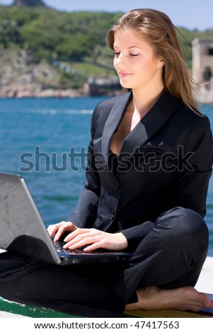 woman in black business suit with laptop sitting near the sea